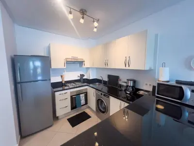 a kitchen with white cabinets and a black counter top at La perle bleue de Beralmar Asilah in Oulad Akkou
