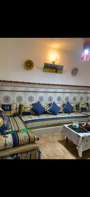 a room with two beds with blue pillows and a table at Apartment a louer sur targha tetouan in Oulad Akkou