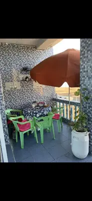 a patio with green tables and chairs and an umbrella at Apartment a louer sur targha tetouan in Oulad Akkou