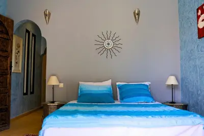 a bedroom with a bed with blue sheets and a clock on the wall at Villa Zazate in Ouarzazate
