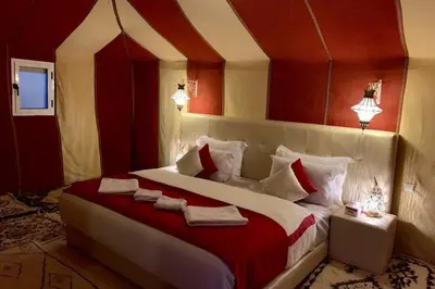 a bedroom with a large bed with red and white pillows at Merzouga Eastern Camp Luxury in Merzouga