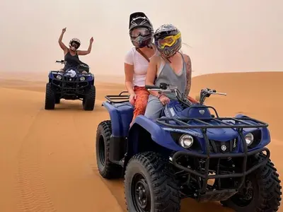 two people riding on atvs in the desert at Merzouga Eastern Camp Luxury in Merzouga