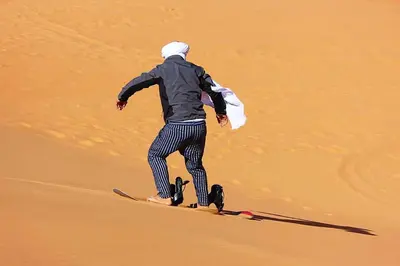 a man standing on a snowboard in the desert at Merzouga Eastern Camp Luxury in Merzouga
