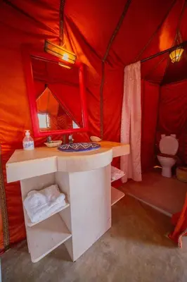 a red tent with a toilet and a sink in it at Azul desert camp in Merzouga