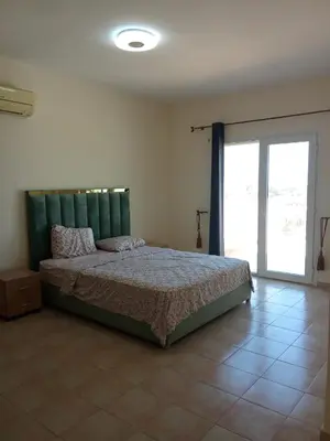 a bedroom with a bed with a green headboard at appartement duplex a saidia in Oulad Akkou