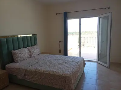 a bedroom with a bed and a sliding glass door at appartement duplex a saidia in Oulad Akkou