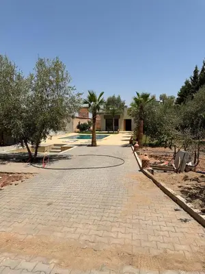 a brick walkway in front of a building with trees at villas par jour in Amezrou