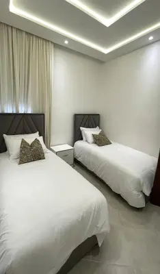 two beds in a hotel room with white sheets at Casa Arabica in Oulad Akkou