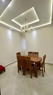 a dining room table with wooden chairs and a chandelier at Casa Arabica in Oulad Akkou