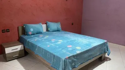 a bedroom with a bed with a blue comforter at Appartement spacieux au cœur de Hamria in Meknès