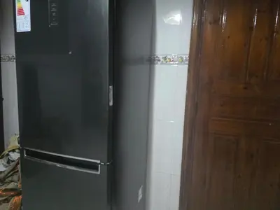 a black refrigerator in a kitchen next to a door at Appartement spacieux au cœur de Hamria in Meknès