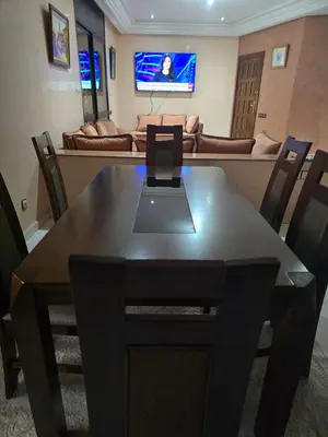 a dining room table with chairs and a living room at Appartement spacieux au cœur de Hamria in Meknès