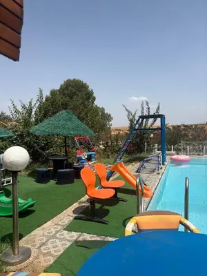 a pool with a playground with chairs and a slide at Gîte à la ferme khemissat
