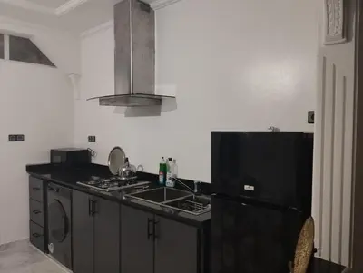 a kitchen with a sink and a black refrigerator at Super appartement quartier paisible proches toutes commodités in Azrou