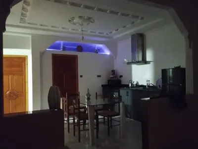 a kitchen with a table and chairs and a blue light at Super appartement quartier paisible proches toutes commodités in Azrou