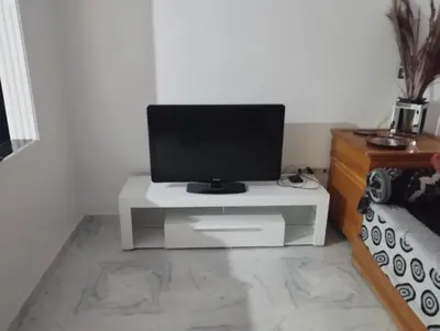 a tv sitting on a white table in a room at Super appartement quartier paisible proches toutes commodités in Azrou