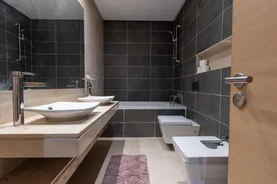 a bathroom with two sinks and a tub and a toilet at Modern 3BR with High Amenities and Stylish Decor in Oulad Akkou
