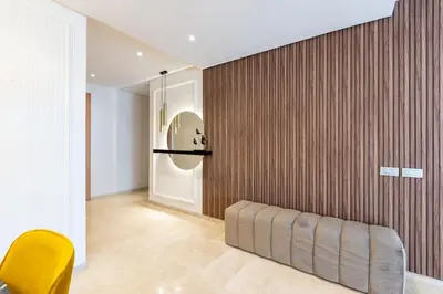 a room with a wooden wall and a yellow chair at Modern 3BR with High Amenities and Stylish Decor in Oulad Akkou