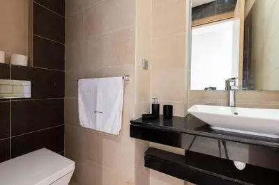 a bathroom with a sink and a toilet and a mirror at Modern 3BR with High Amenities and Stylish Decor in Oulad Akkou