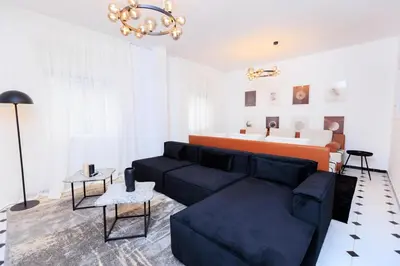 a living room with a black couch and a chandelier at Modern Elegance 2BR in the Heart of Agdal in Oulad Akkou