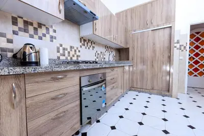 a kitchen with wooden cabinets and a dishwasher at Modern Elegance 2BR in the Heart of Agdal in Oulad Akkou