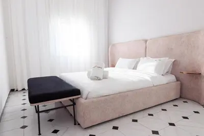 a bedroom with a bed with a chair and a white bedvisor at Modern Elegance 2BR in the Heart of Agdal in Oulad Akkou