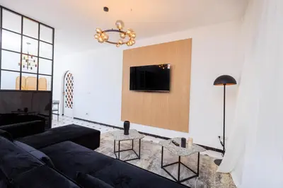 a living room with a couch and a tv on a wall at Modern Elegance 2BR in the Heart of Agdal in Oulad Akkou