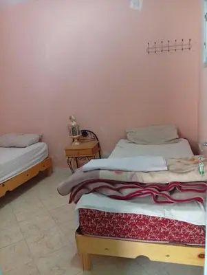 two twin beds in a room with a table at auberge djebel rose 03 in Oulad Akkou