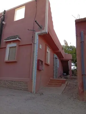 a red house with a door and stairs on it at auberge djebel rose 03 in Oulad Akkou