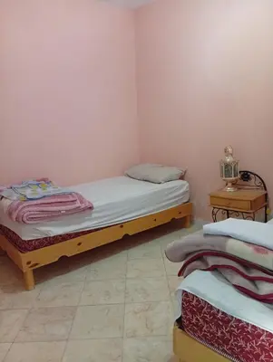 a bedroom with two twin beds and a table at auberge djebel rose 03 in Oulad Akkou