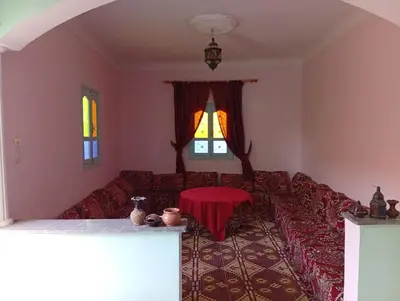 a living room with a red couch and a table at auberge djebel rose 03 in Oulad Akkou