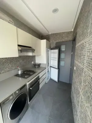 a small kitchen with a stove and a refrigerator at Modern Pool-View Luxury Flat in Oulad Akkou
