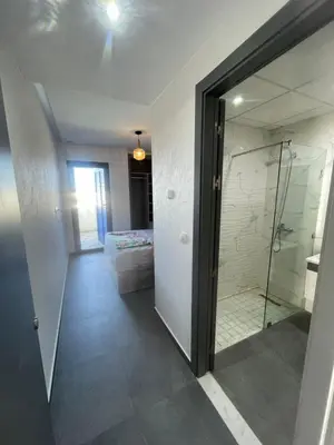 a bathroom with a shower and a glass door at Modern Pool-View Luxury Flat in Oulad Akkou