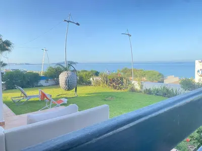 a balcony with a view of a garden and the ocean at Seaside Villa with Stunning View in Oulad Akkou