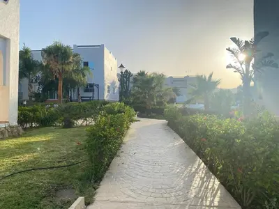 a walkway in a park with palm trees and a building at Seaside Villa with Stunning View in Oulad Akkou