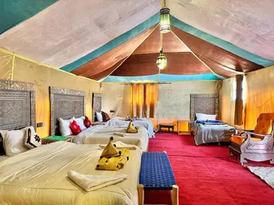 a bedroom with four beds and a tent at sunshine luxury camp in Merzouga