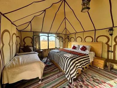 a bedroom with two beds in a tent at sunshine luxury camp in Merzouga