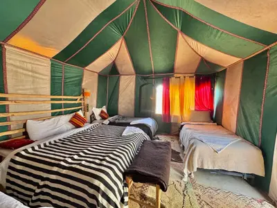 a room with a tent with two beds in it at sunshine luxury camp in Merzouga