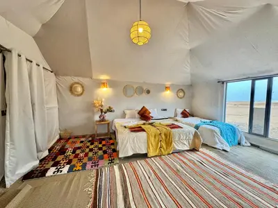 a bedroom with two beds in a tent at sunshine luxury camp in Merzouga