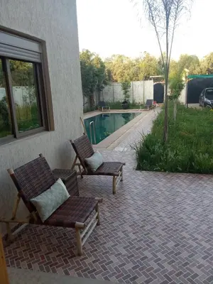 two chairs sitting on a patio next to a swimming pool at charmante villa à découvrir in Aghmat