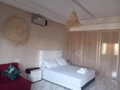 a bedroom with a white bed and a red couch at charmante villa à découvrir in Aghmat