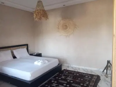 a bedroom with a white bed and a rug at charmante villa à découvrir in Aghmat