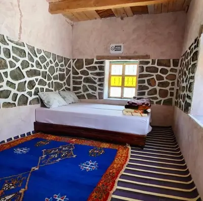 a bed in a room with a stone wall at Gîte Jamal taghia in Taghia