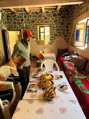 a man standing in front of a table with food at Gîte Jamal taghia in Taghia