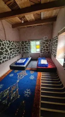 a room with two beds and a rug at Gîte Jamal taghia in Taghia