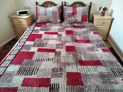 a bed with a red and white quilt on it at Stay 5 minutes from Fes airport in Oulad Tayeb