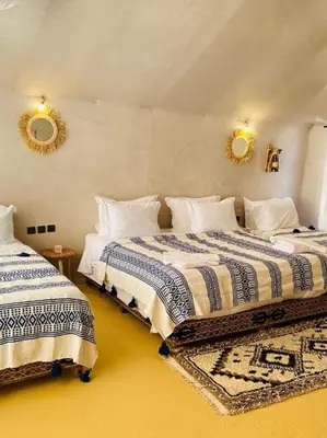 two beds in a bedroom with two mirrors on the wall at Sunlight Luxury Desert Camp in Merzouga