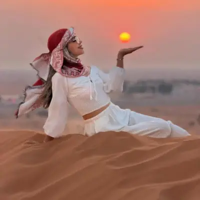 a woman in the desert with the sun in at Sunlight Luxury Desert Camp in Merzouga