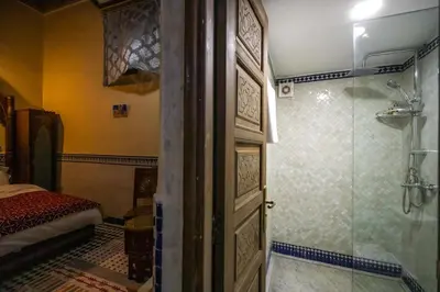 a bathroom with a shower and a door to a bedroom at Saphiryad in Fès