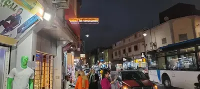 a group of people walking down a city street at night at JMEL B&b